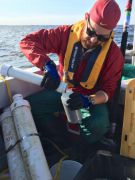Adam Heathcote collects a suspended sediment sample from a buoy station on Lake of the Woods.